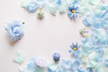 白背景に造花の青い花と花びらで囲んだフレーム。平置きの俯瞰撮影。