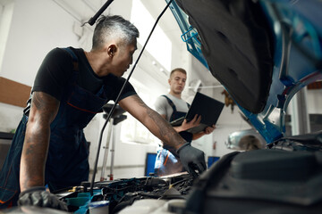 Mechanics doing computer diagnostic of car engine