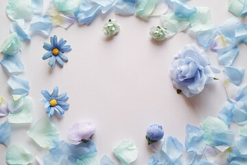 Obraz na płótnie Canvas 白背景に造花の青い花と花びらで囲んだフレーム。平置きの俯瞰撮影。