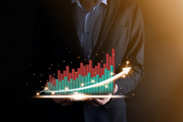 Businessman holding and showing a growing virtual hologram of statistics, graph and chart with arrow up on dark background. Stock market. Business growth, planing and strategy concept.