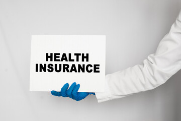 The doctor's blue - gloved hands show the word HEALTH INSURANCE - . a gloved hand on a white background. Medical concept. the medicine
