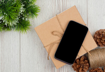 Fashion Gift. smartphone and fir branches on wooden background. Black Friday sale concept. gifts and phone. flat lay.