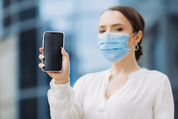 business woman in a protective mask holding a phone