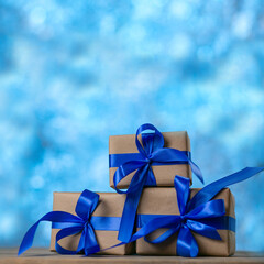 Christmas gift boxes with blue ribbons against blue lights garland and bokeh background. Holiday greeting card. Square image