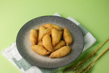 Pisang Molen, Indonesian traditional street food, made from banana fruits stuffed with pastry dought and cooked with deep fry step.Served on grey ceramic plate,  Isolated green background.