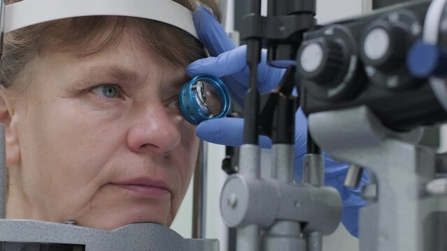 Woman doctor is viewing through ophthalmoscope in eyes of patient in ophthalmologic clinic. Professional inspection of vision