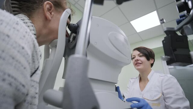 Woman doctor is viewing through ophthalmoscope in eyes of patient in ophthalmologic clinic. Professional inspection of vision
