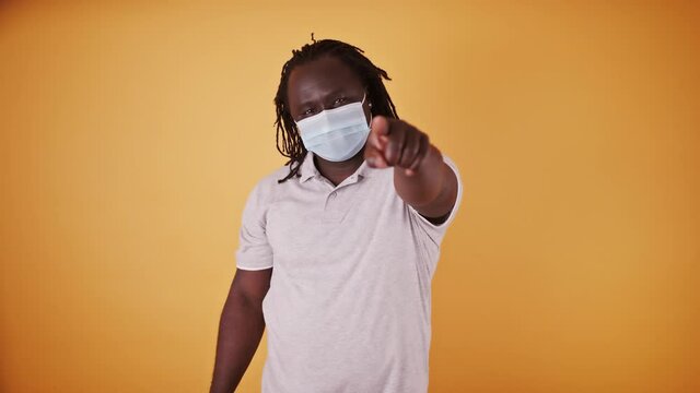African american black man with medical mask and braidd hair pointing finget towards the camera. High quality 4k footage