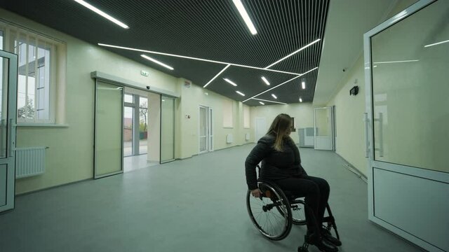 Disabled woman in wheelchair at home comes in to modern office building
