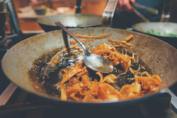 Karottenstreifen mit Öl in einer alten Pfanne beim Anbraten