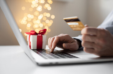 Shopping online during holidays. Man using laptop computer and credit card ordering Christmas...