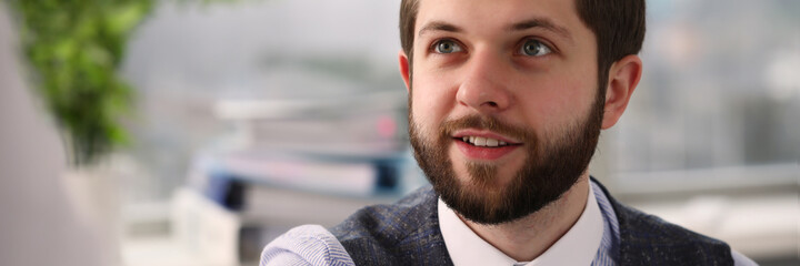 Obraz premium Positive delighted bearded office worker keeping smile on his face while shaking hands with business partner