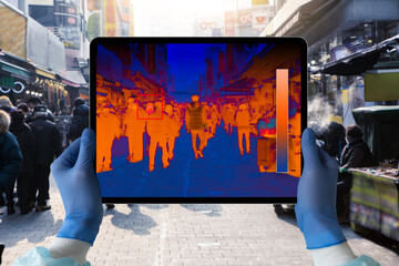 Hands with digital tablet with a thermal imager. Finding people with high fever in the crowd