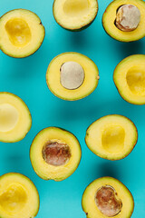 Cut fresh ripe avocados with and without pits on blue background