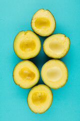 Halves of avocados without pits on light blue background