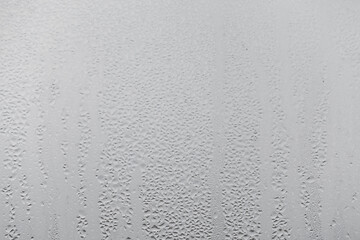 Close up water drop on grey background, misted glass with droplets of water draining down. Dripping Condensation