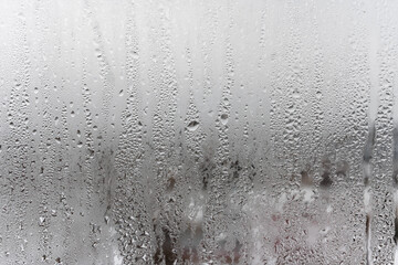 Close up water drop on grey background, misted glass with droplets of water draining down. Dripping Condensation