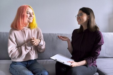 Teen girl giving interview to social worker. School psychologist talking with student