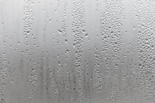 Close up water drop on grey background, misted glass with droplets of water draining down. Dripping Condensation