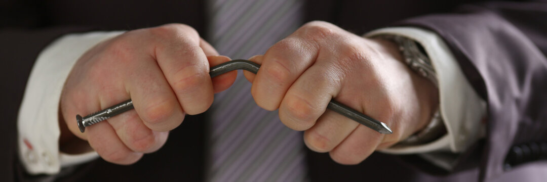 Angry businessman deforming metal thing while expressing his unsatisfaction after meeting with partners