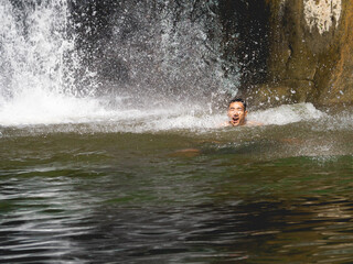 A man swimming in a waterfall
