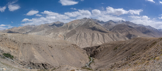 Panoramic view of the snow-capped Wakhan mountain range in Afghanistan from the high-altitude desert between Langar and Khargush pass in Gorno-Badakhshan, Tajikistan Pamir