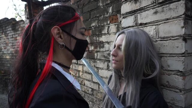 Long haired asian man caught the woman and put the sword to her neck. Cosplay scene
