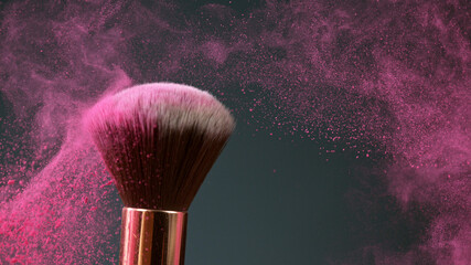 Makeup brushes touch each other on dark background and small particles of cosmetics