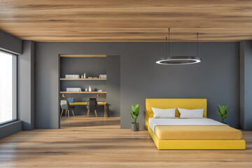 Grey wooden bedroom with yellow bed and workplace with chairs