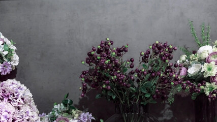 Fragment of a bouquet vintage beautiful of different artificial flowers and berries in boroco style, floral arrangement decorative dark background with plants in purple green tones with copy space