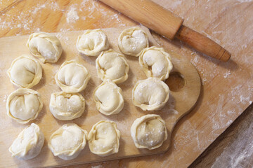 Closeup on semi-finished pelmeni dumplings on the wooden board.