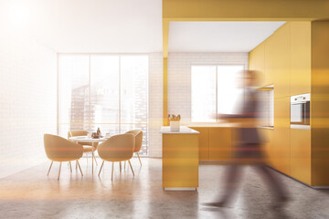 Man walking in yellow kitchen with table
