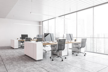 White office room with armchairs and computers on the tables near window