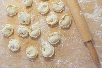 Closeup on semi-finished pelmeni dumplings on the wooden board.