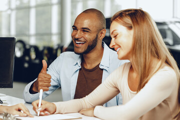 Happy couple signing contract at car dealership