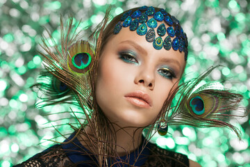 Beautiful fashion woman face. Woman in peacock image with peacock feathers.