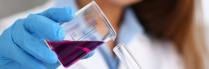 Professional researcher wearing uniform while working with reagents in laboratory, doing chemical experiment