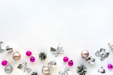 Christmas flat lay of silver and pink decorations. Balls, cones and bows on white background, space for text