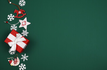 Christmas wooden decorations and red gift box on green tidewater background with copy space