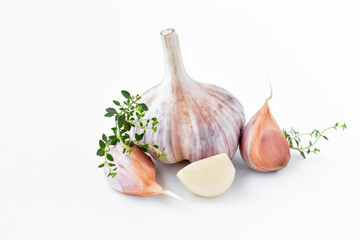 Whole garlic and cloves with two sprigs of thyme on a white plate. Close-up. Isolate.