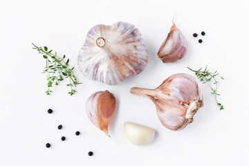 Garlic, aromatic herb thyme and black peppercorns on a white background. Top view, close-up.