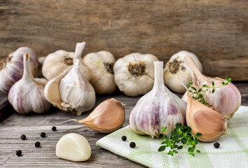 Garlic on a wooden, rustic table, a branch of thyme and black peppercorns. A bunch of fresh garlic, peeled cloves.