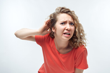 Image of pretty blonde girl holding hand near ear trying to listen something. Human emotions,...