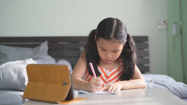 asian child student back to school or kid girl write and read on computer tablet with doing homework to thinking and use eraser or people learn from home in bedroom and study online on smartphone 4K