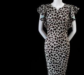  White mannequin in a fashionable sheath dress with a large spotted print on a black background. Elegant clothes for women. Copy space for text.