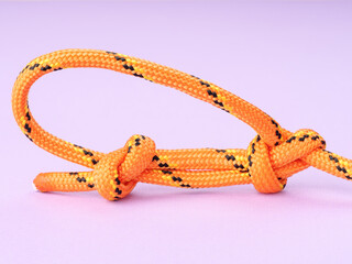 Bowline knot made of nylon rope on a pastel purple background.