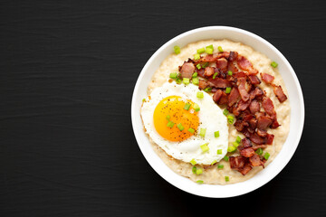 Homemade Cheesy Bacon Savory Oatmeal Bowl on a black background, top view. Overhead, from above, flat lay. Copy space.