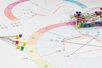 Workplace of a modern astrologer. Scattered on the table are printouts of astrological charts,...