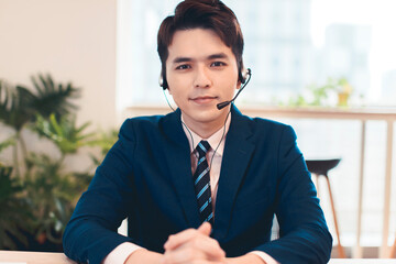 Head shot portrait confident young businessman  looking at camera and talking by headphone.