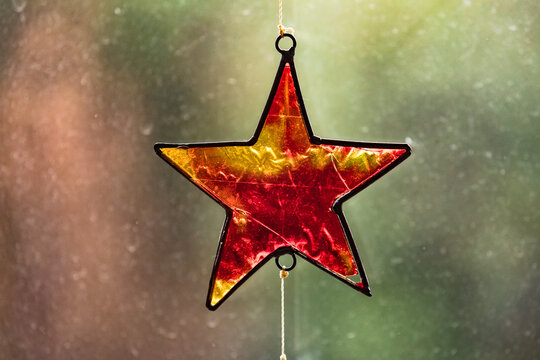 Ein Stern aus rotem und gelbem Glas dient im Gegenlicht als Weihnachtsdeko